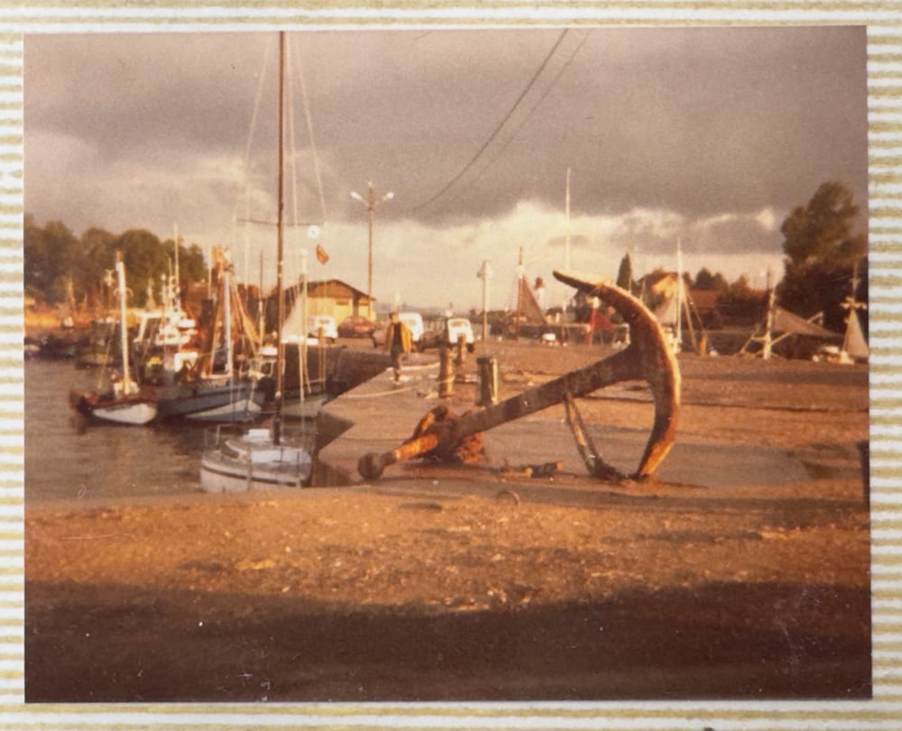 A harbour at low tide with a large anchor in the foreground, Northern France